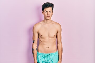 Fototapeta premium Young hispanic man wearing swimwear shirtless skeptic and nervous, frowning upset because of problem. negative person.