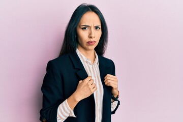 Young hispanic girl wearing business clothes skeptic and nervous, frowning upset because of...