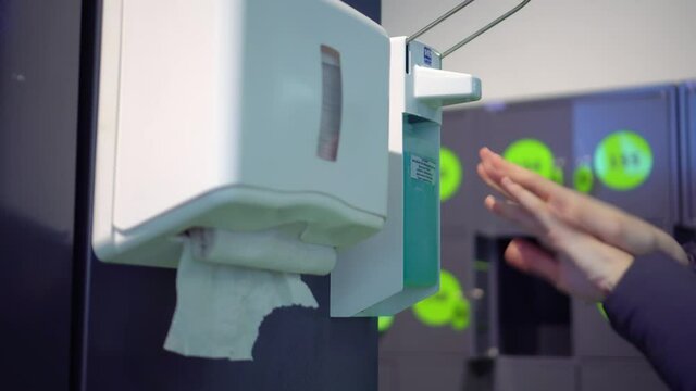 A woman uses a general antiseptic in a public place, which stands for customers at the entrance to the store. the concept of the virus and the coronavirus pandemic. and he wipes himself off with a pap