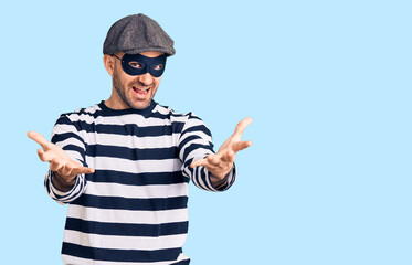 Young handsome man wearing burglar mask smiling cheerful offering hands giving assistance and acceptance.