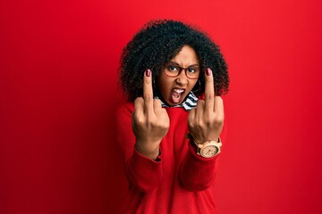 Beautiful african american woman with afro hair wearing sweater and glasses showing middle finger...