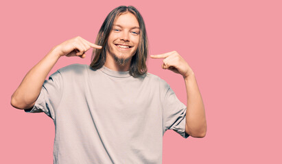 Handsome caucasian man with long hair wearing casual clothes smiling cheerful showing and pointing with fingers teeth and mouth. dental health concept.