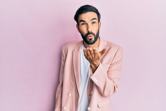 Young hispanic man wearing business jacket looking at the camera blowing a kiss with hand on air being lovely and sexy. love expression.