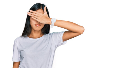 Obraz na płótnie Canvas Beautiful young asian woman wearing casual white t shirt covering eyes with hand, looking serious and sad. sightless, hiding and rejection concept