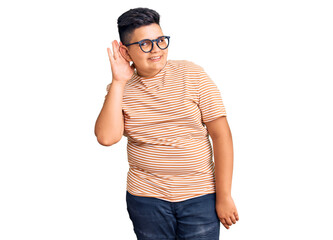 Fototapeta premium Little boy kid wearing casual clothes and glasses smiling with hand over ear listening an hearing to rumor or gossip. deafness concept.