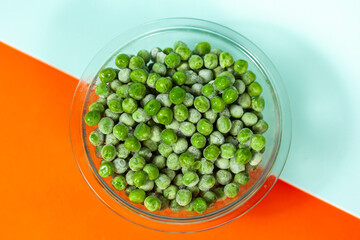 bowl with frozen peas on orange and light blue background