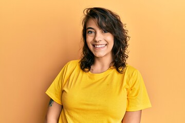 Young hispanic woman wearing casual yellow t shirt with a happy and cool smile on face. lucky person.