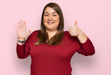 Beautiful brunette plus size woman wearing casual clothes showing and pointing up with fingers number six while smiling confident and happy.