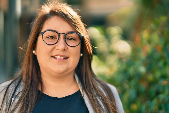 Young hispanic plus size businesswoman smiling happy standing at the city.