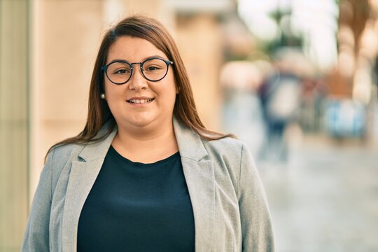 Young hispanic plus size businesswoman smiling happy standing at the city.