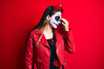 Woman wearing day of the dead costume over red tired rubbing nose and eyes feeling fatigue and headache. stress and frustration concept.