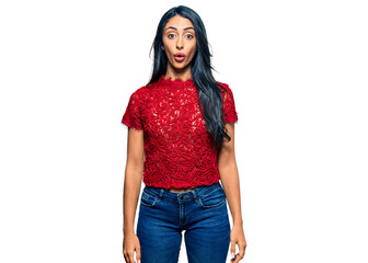Beautiful hispanic woman wearing elegant shirt scared and amazed with open mouth for surprise,...