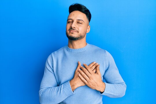 Young arab man wearing casual clothes smiling with hands on chest, eyes closed with grateful gesture on face. health concept.