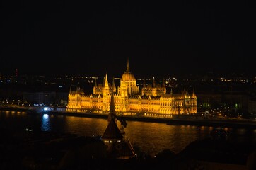 Fototapeta na wymiar Night view of illuminated beautiful Parliament building across river Danube in Budapest, Hungary