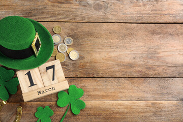 Leprechaun's hat, block calendar and St. Patrick's day decor on wooden background, flat lay. Space...