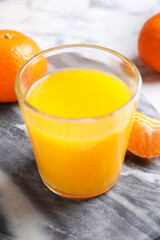 Naklejka na ściany i meble Glass of fresh tangerine juice and fruits on board