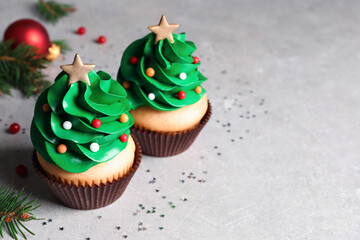 Christmas tree shaped cupcakes on light grey table. Space for text