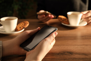 Women using mobile phones at table in cafe, closeup