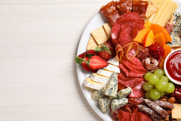 Plate of different appetizers with dip sauce on white wooden table, top view. Space for text