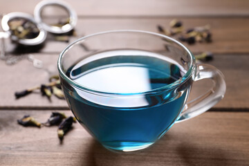 Obraz na płótnie Canvas Glass cup of organic blue Anchan on wooden table, closeup. Herbal tea