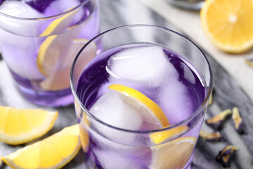 Organic blue Anchan with lemon and ice cubes on table, closeup. Herbal tea