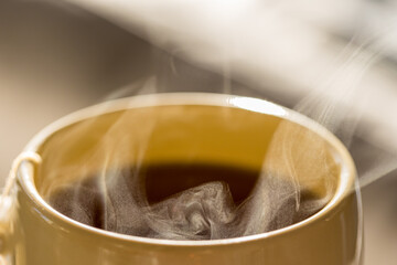 Steaming hot drink in ceramic cup close up view