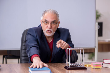 Old teacher physicist sitting in the classroom