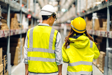Asian two engineer in helmets team order details on tablet computer for checking goods and supplies on shelves with goods background in warehouse.logistic and business export