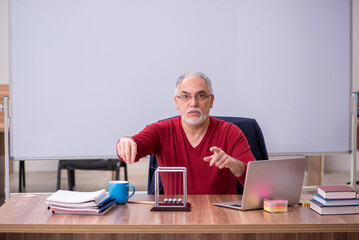 Old teacher physicist sitting in the classroom