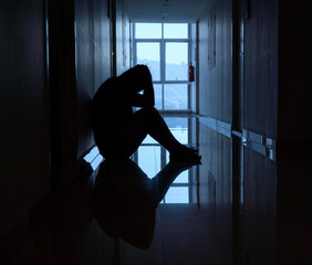 man sit down Hallway in Apartment after failure and laid off from work because impact from covid-19 .