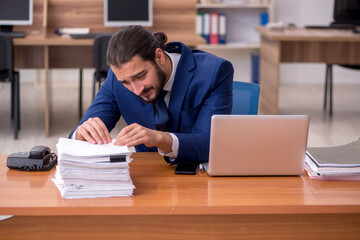 Obraz premium Young businessman employee unhappy with excessive work in the of