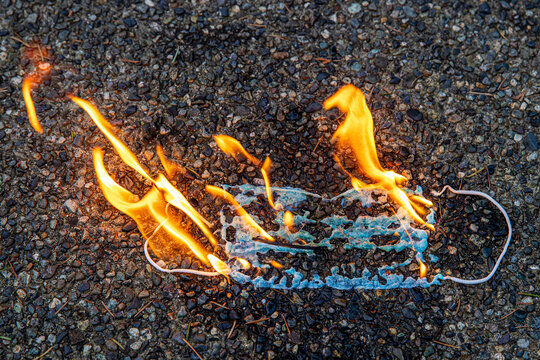 A medical face mask burns in flames as the coronavirus pandemic ends. The fire represents a protest of the mask mandate imposed by government officials during the Covid-19 virus outbreak. 