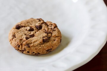 A close up shot of some delicious homemade chocolate chip cookies on a white ceramic plate.