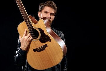 Obraz premium A man with a guitar in his hands leather jacket music performance rock star modern style dark background