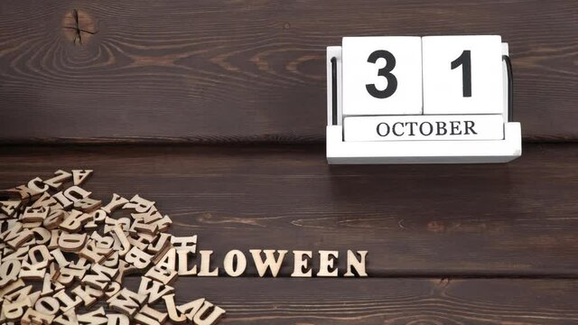 October 31, date on the calendar.  Handmade wood cube with date month and day. halloween holiday. flying wooden letters, carved letters of the English alphabet. word halloween appears. slow motion.