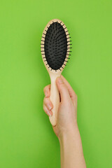 hand with comb. Hand holds a bamboo hairbrush. Ecological hygiene items. Bamboo comb. Zero waste