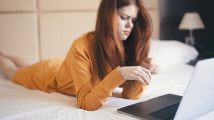 woman lies in bed in front of laptop emotions technology freelance