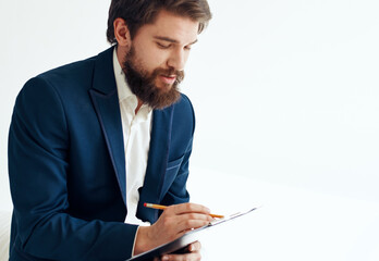 A man in a jacket and shirt with documents on his knees