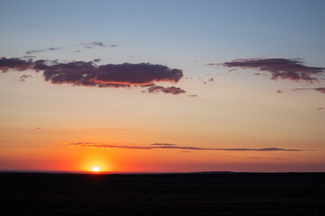 Fototapeta na wymiar Crimson summer sunset that dramatically highlights clouds in Kazakh steppe.