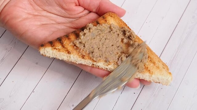 Woman smear chicken pate on toast, making sandwiches for breakfast.
