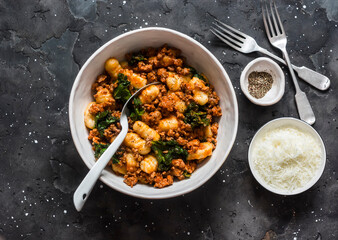 Turkey hash with potato gnocchi on a dark background, top view