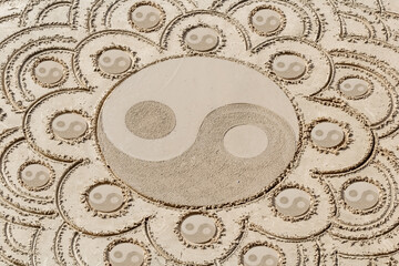 Motifs yin yang tracés sur le sable de plage 