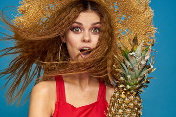 Woman in a straw hat with pineapple in her hands wavy hair exotic fruits you summer blue background vacation