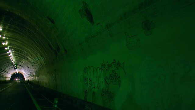 Slow motion shot of vehicles in dark tunnel with graffiti on wall at night - Los Angeles, California
