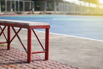 A cast iron red bench in the basketball court.