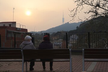 2 mujeres mayores hablan sentadas con mascarilla