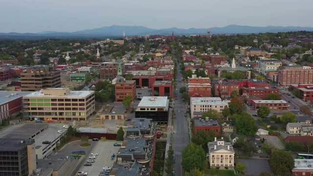 Aerial shot of vehicles on street amidst buildings in city, drone flying forward over structures against sky at sunset - Burlington, Vermont