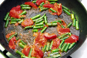 Tomato and green beans roasted on the black frying pan for morning roasted whole eggs