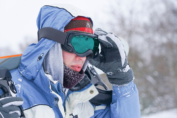 Portrait of a snowboarder on a snowy slope. Freerider with a snowboard in a hat and a mountain mask