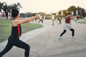Rearview of matured healthy people doing aerobics dance in the city park in the evening after work to relax and get a healthy life. Sports and recreation